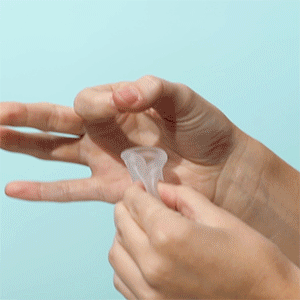Gif of someone inserting a menstrual cup in between a hold made with thumb and forefinger