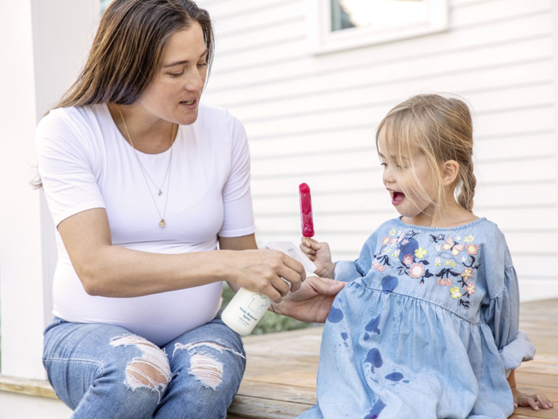 Image of a woman spraying stains on a child's clothes