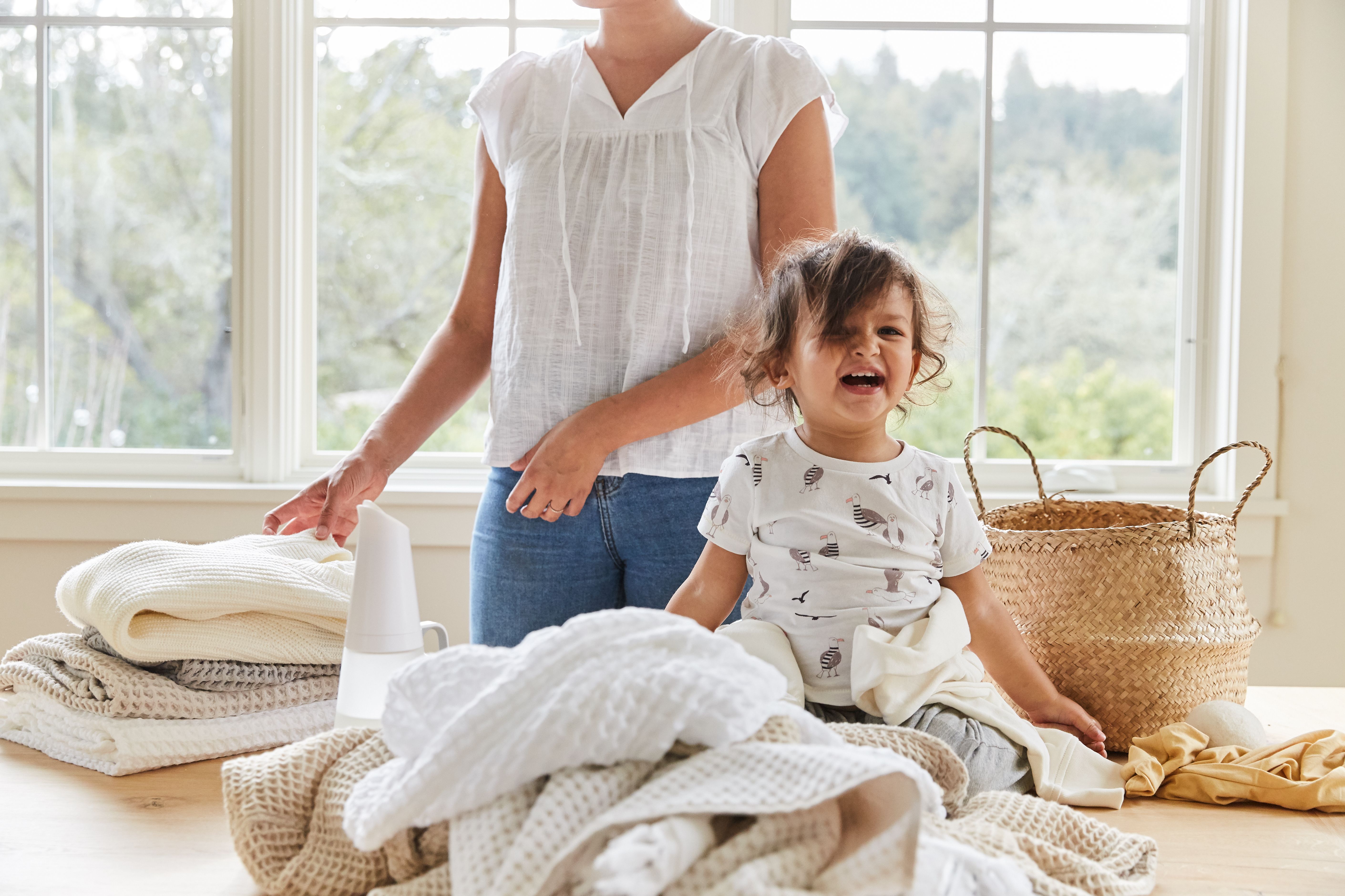 woman and happy baby surrounding by clean laundry