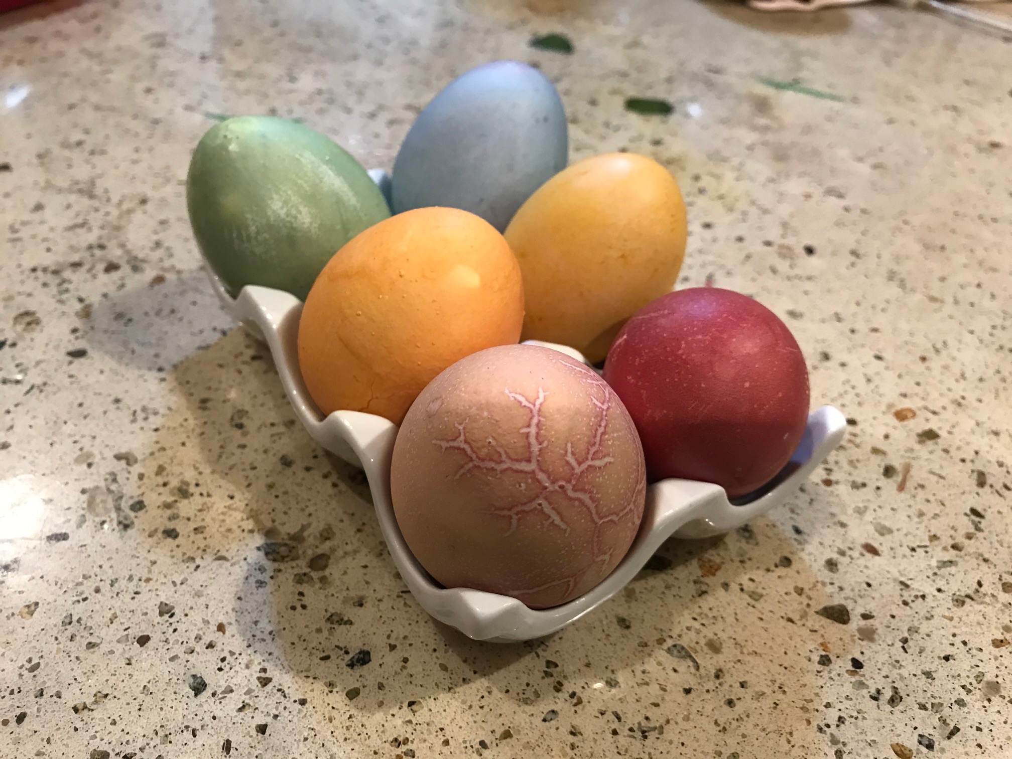 naturally dyed Easter eggs in a ceramic egg holder