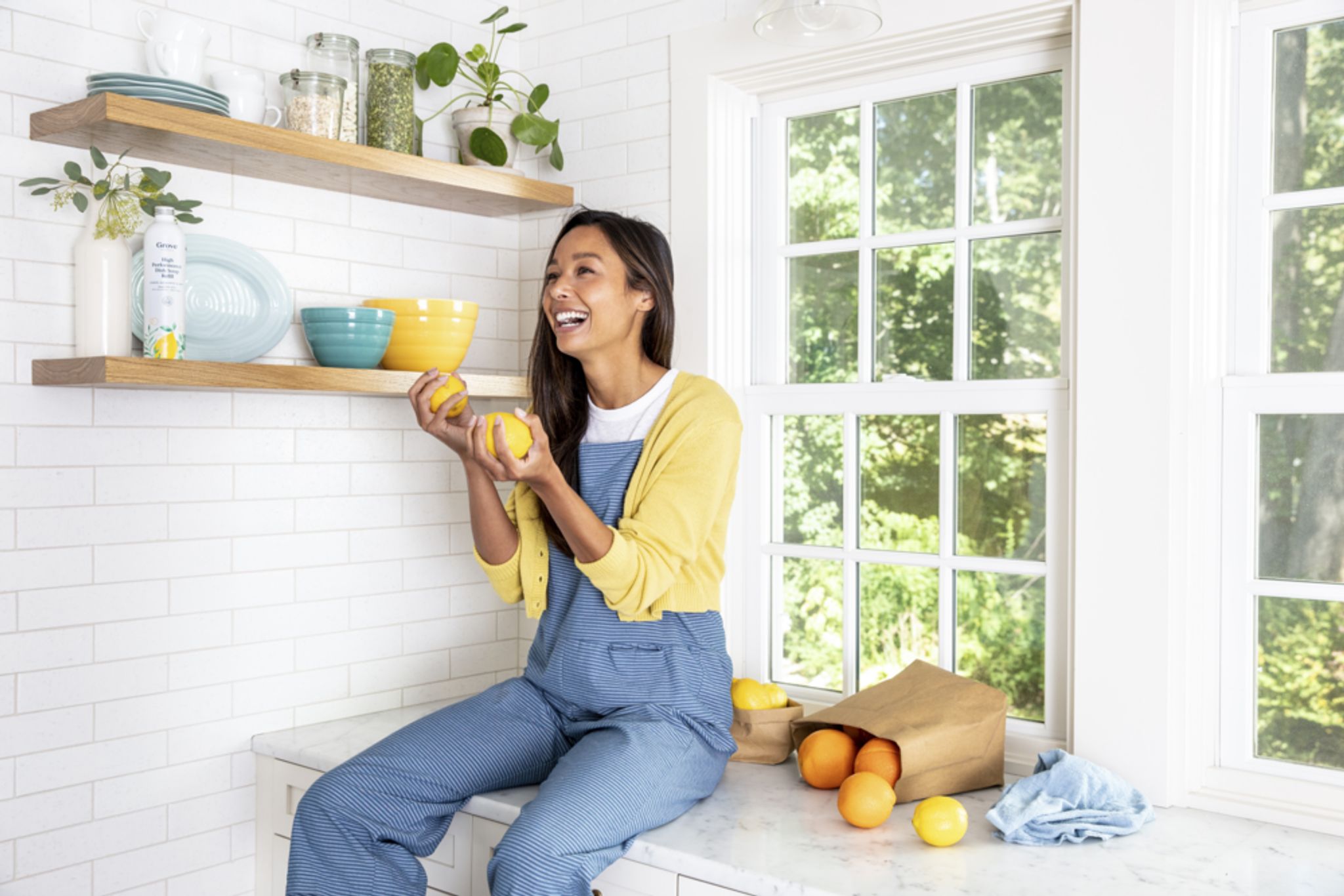 Woman sitting on counter holding fruit