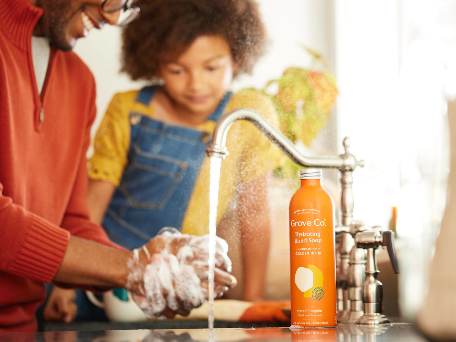 Image of parent washing hands in sink with Grove Pumpkin Spice hand soap with child watching on side
