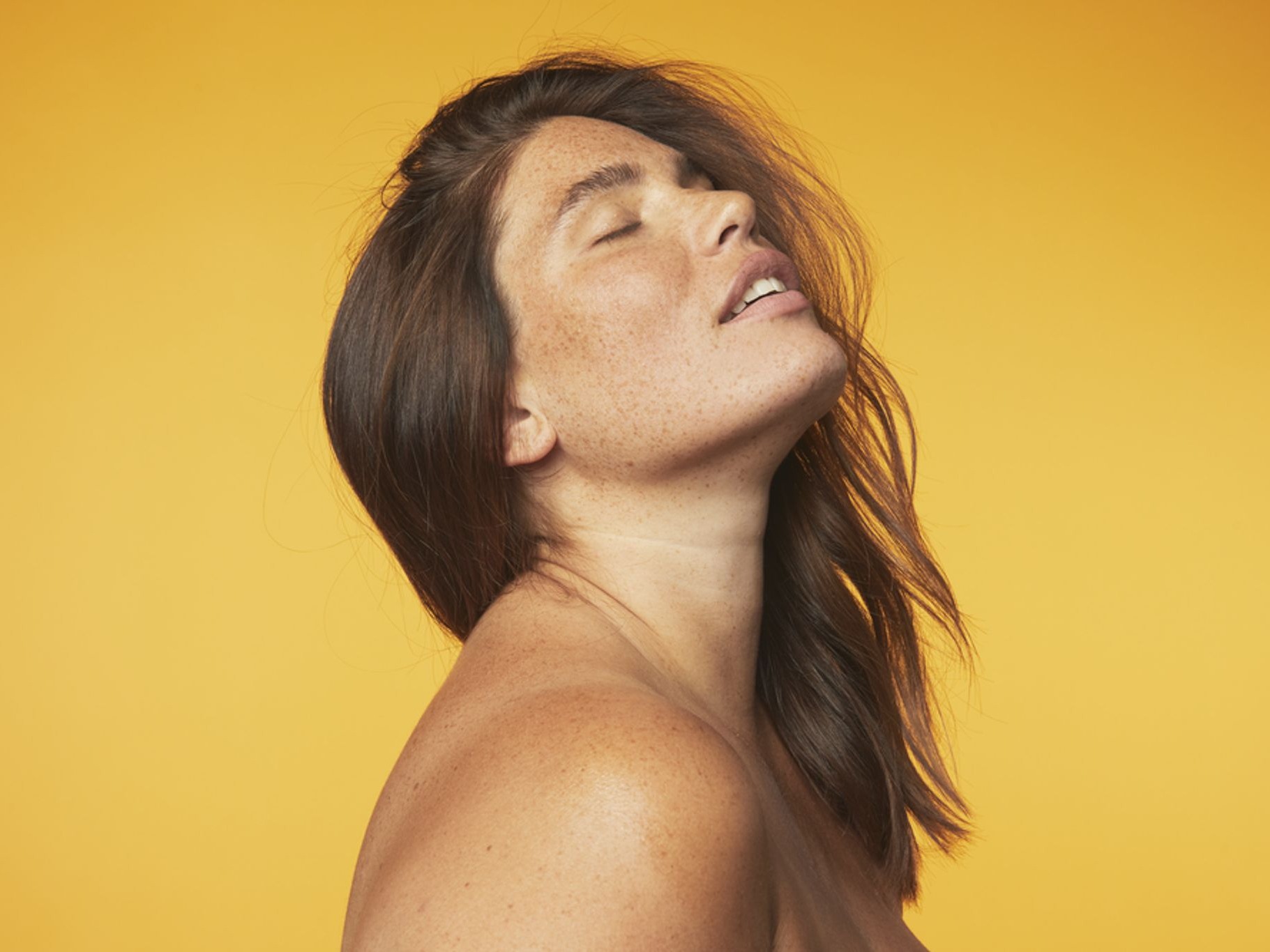 Woman with eyes closed against yellow background