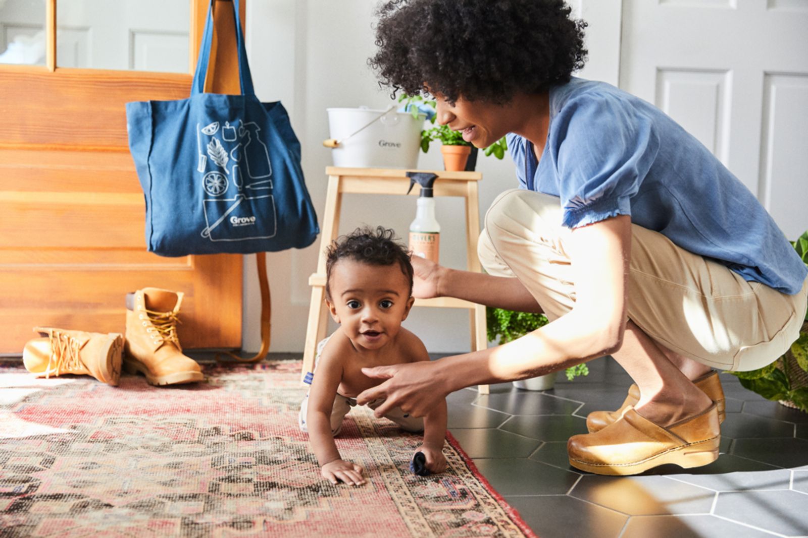 Image of mom helping young baby crawl across carpet