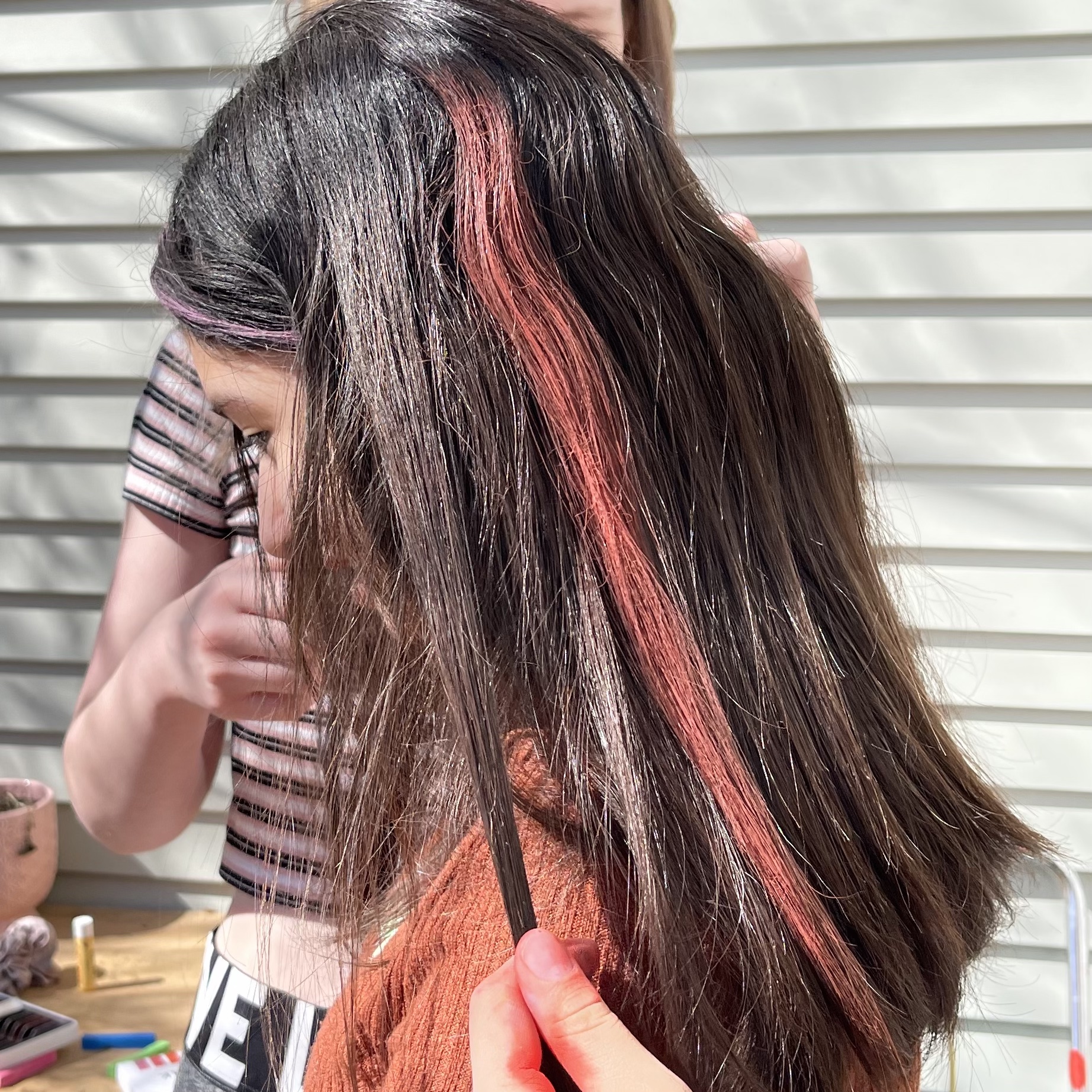 a vivid red streak from hair chalk in a child's long black hair