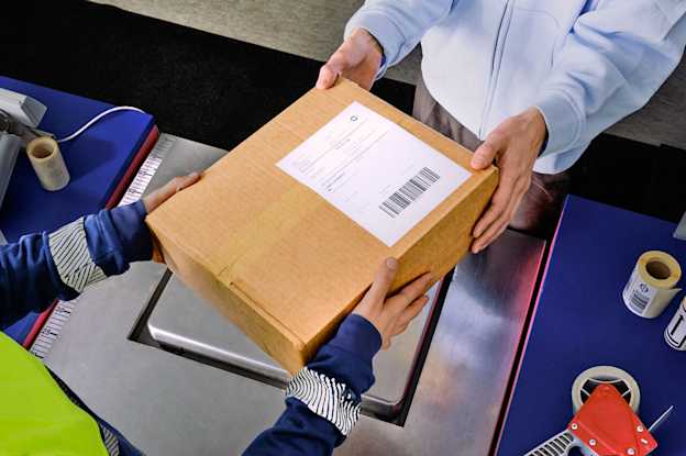 En kund lämnar över ett paket till en anställd vid Matkahuoltos serviceställe.