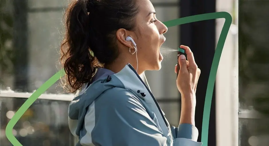 Kvinne sprayer Nicorette munnspray i munnen mens hun er på farten