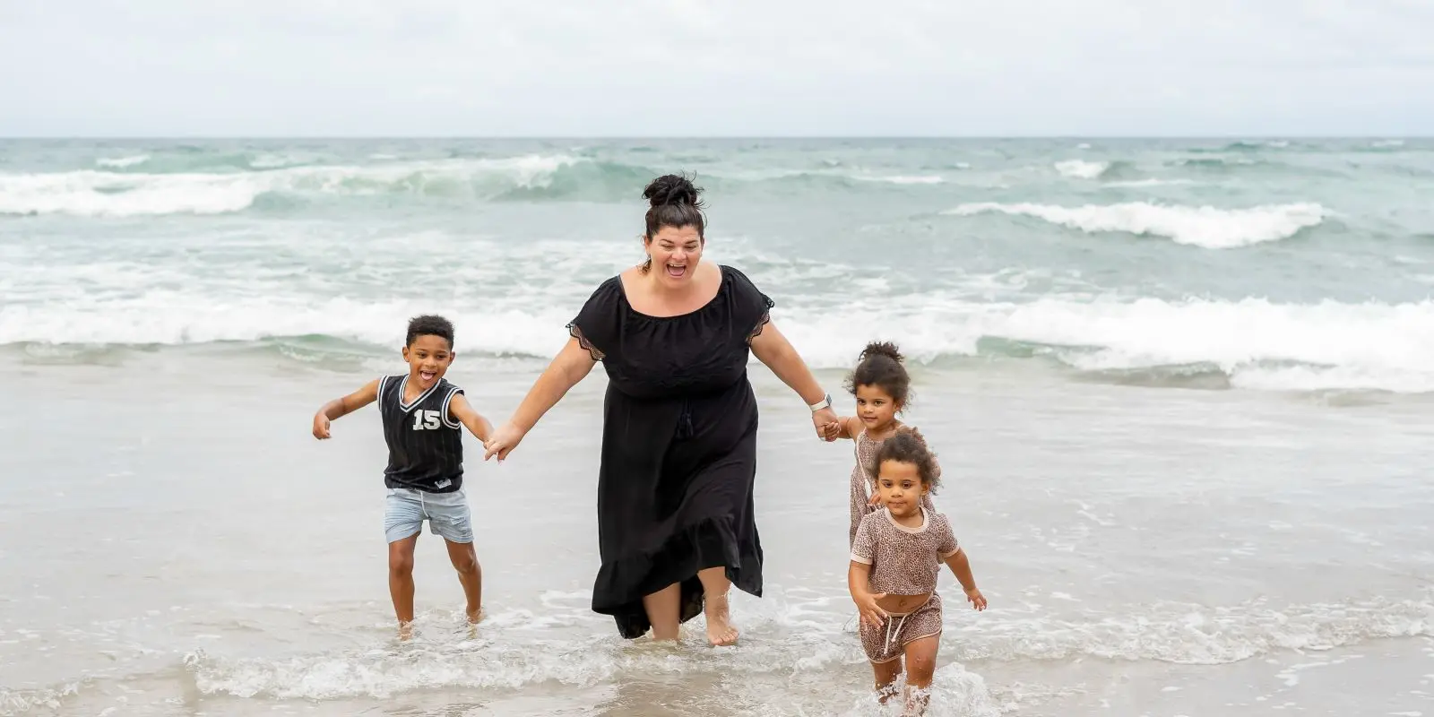 Woman and three children playing in the sea
