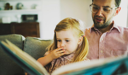 Image of a father and daughter reading a book. 