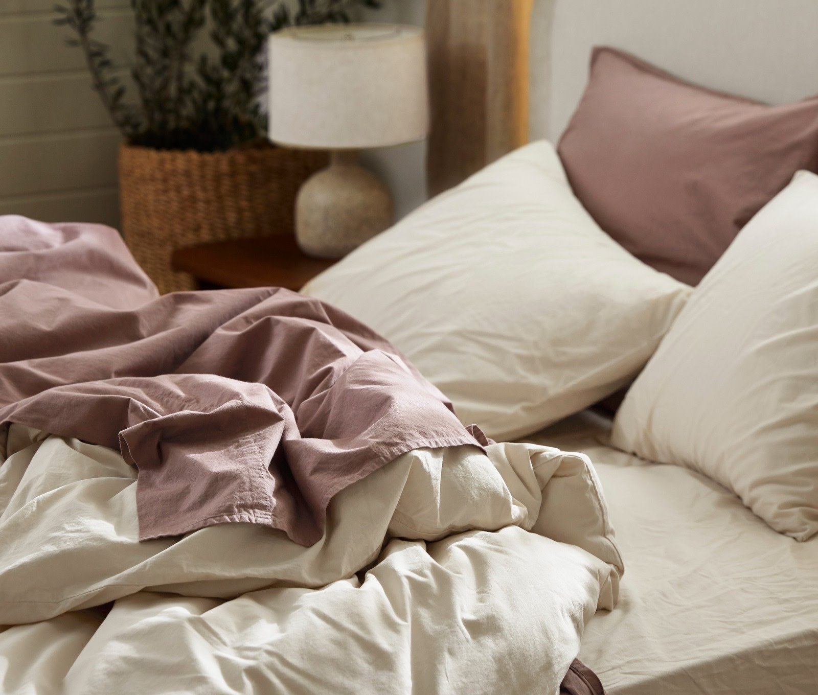 An unmade bed with ivory and clover brushed cotton sheets