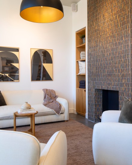 Living room with plush ivory sofas and chairs next to a stone fireplace