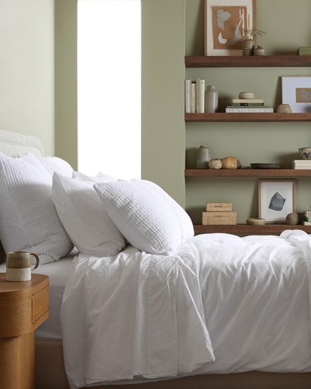 A neat bed with white organic cotton sheets