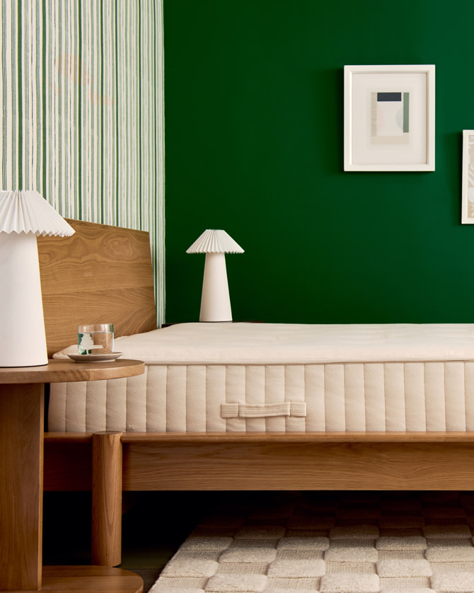 Side angle of bare mattress against green wall