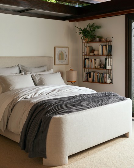 A moody bedroom with a bed made up of white and light grey sheets