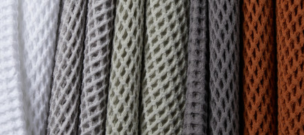 Waffle towels in white, light grey, willow, dark grey, and terra hanging in a tow