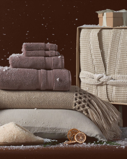 A festive assortment of giftable items including a robe, towels, throw blankets, and slippers 