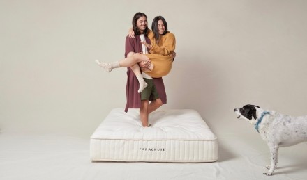 Couple in robes on mattress with dog.