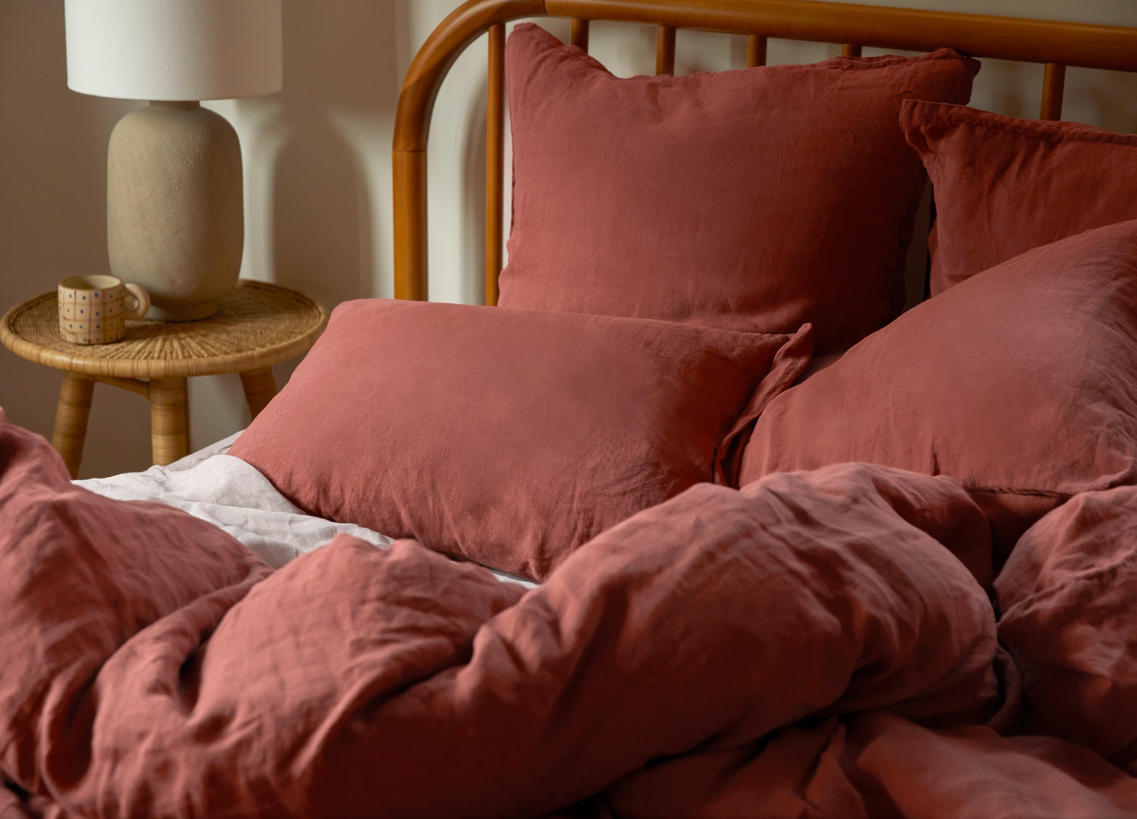 A bed with canyon-red linen sheets