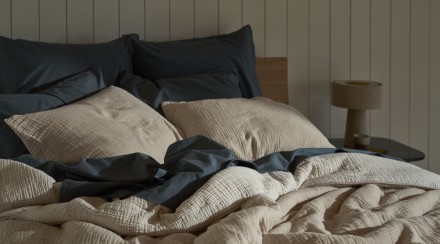 A messy bed with dusk brushed cotton sheets and a natural and ivory organic cloud cotton quilt