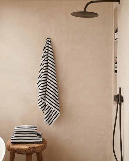 Folded and stacked resort stripe towels in a tan colored shower