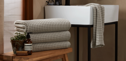 Stack of willow colored waffle towels in a bathroom