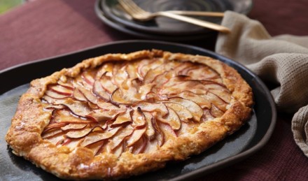 Apple galette on burgundy table cloth with plates. 