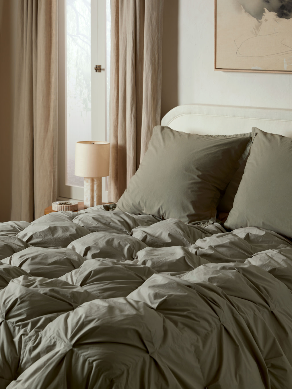 Moss green bedding and organic cotton puff comforter on a bed