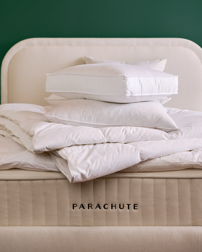 Stack of bare pillow and duvet inserts on top of a mattress