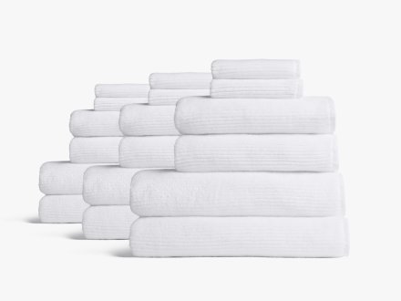 Stack of bath towels on wooden background. White and pink fluffy