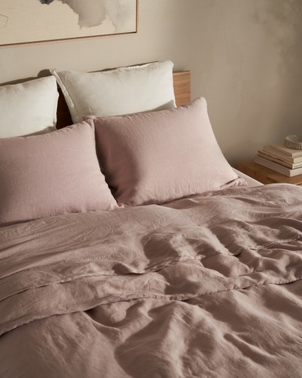 A bed with dusty grayish purple linen sheets