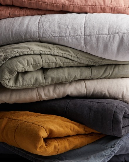 A stack of linen box quilts in various colors