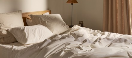 A rumpled bed with white and bone percale sheets