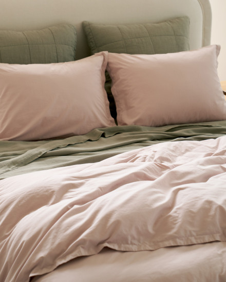 A bed with haze and moss percale sheets