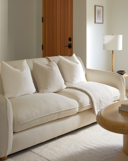 A pristine, plush ivory sofa with neatly arranged throw pillows