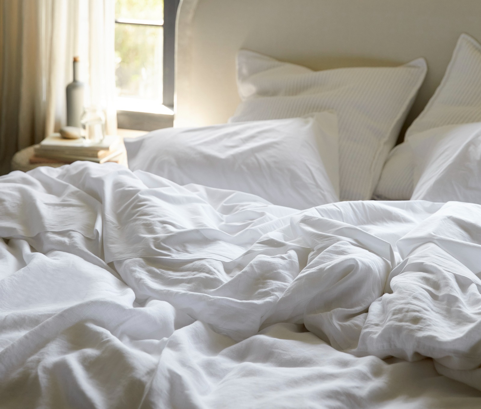 A person in a bed with evergreen linen sheets