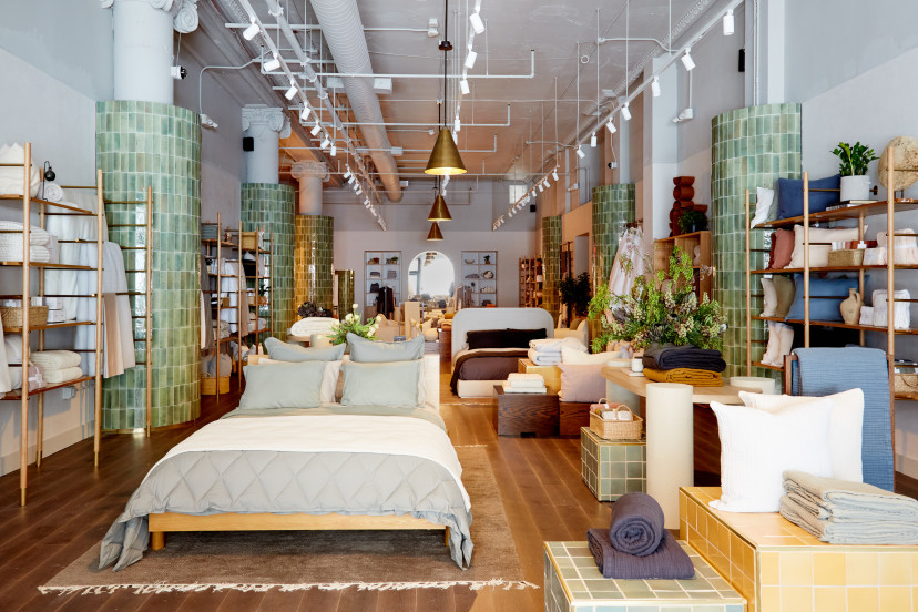 A Parachute store with neatly made beds and shelving full of plush pillows and blankets