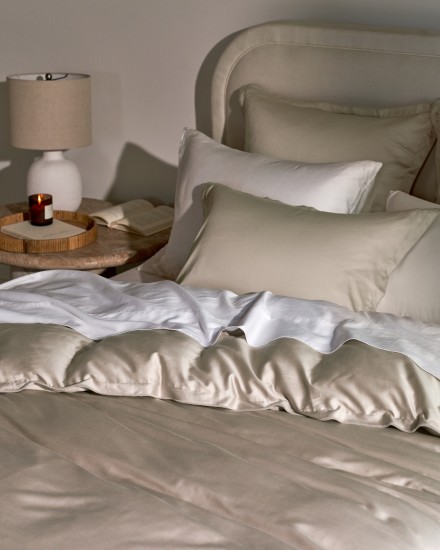 A luxurious bed with bone and white sateen sheets