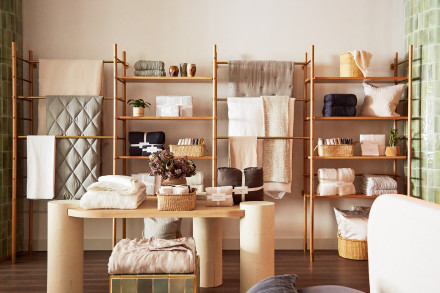 Wooden shelves full of hanging and folded blankets, sheets, and pillows