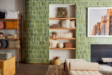 A green-tiled wall in a Parachute store with shelves of decorative pillows and blankets