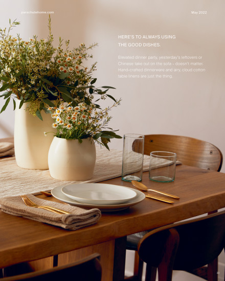 A wooden dinner table with Parachute table linens and dinnerware.