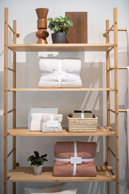 Blankets and quilts folded neatly on a light wood shelf.