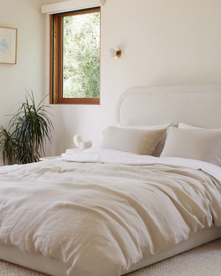 A bed with bone and white linen sheets