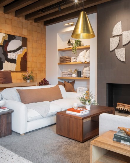 A sitting area with cozy white sofas in front of a grey tile fireplace