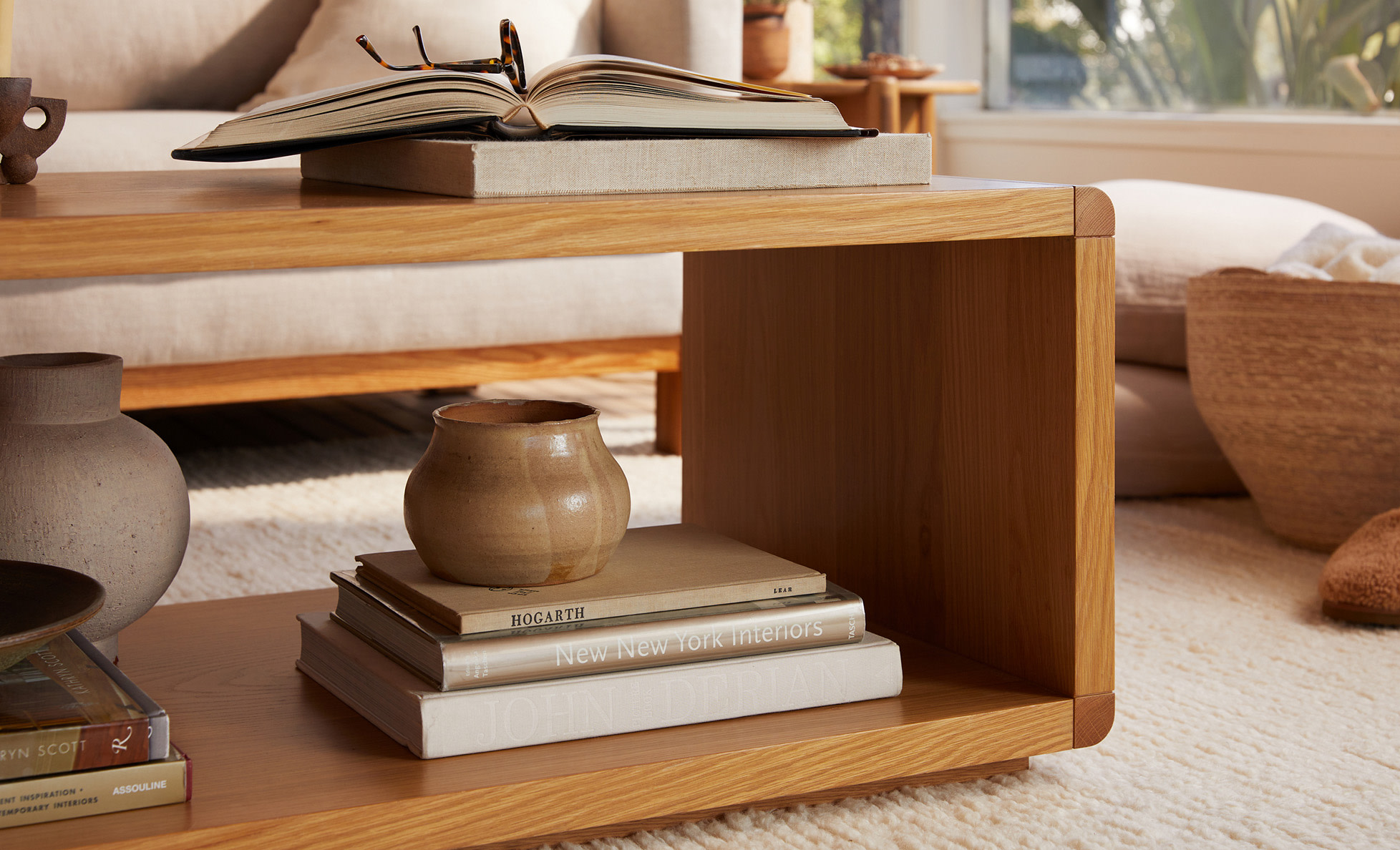 A white oak coffee table with decorative books and accessories stacked inside