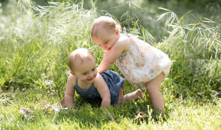 Two babies playing in jumpsuits