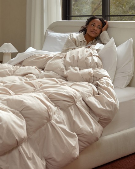 A woman sitting in a bed with a puffy cotton comforter