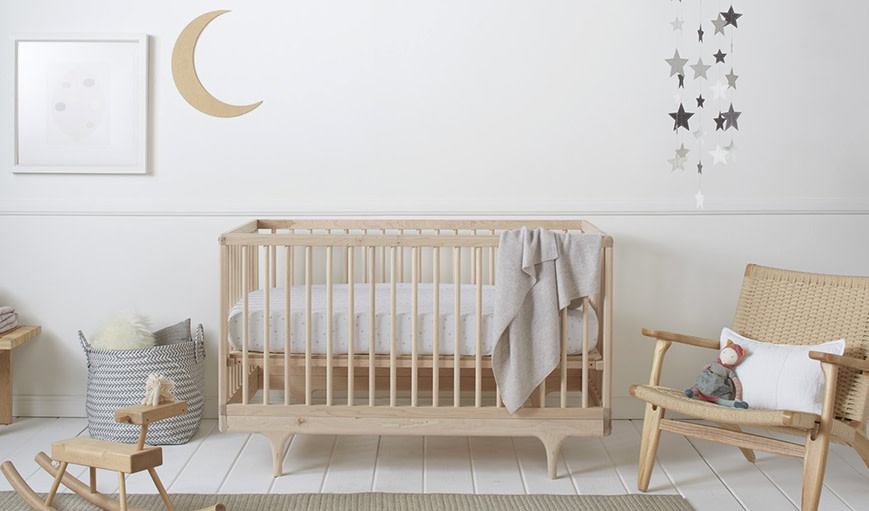 A crib with a cashmere baby blanket draped over the side. 