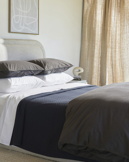 A neat bed with white and shale organic cotton sheets