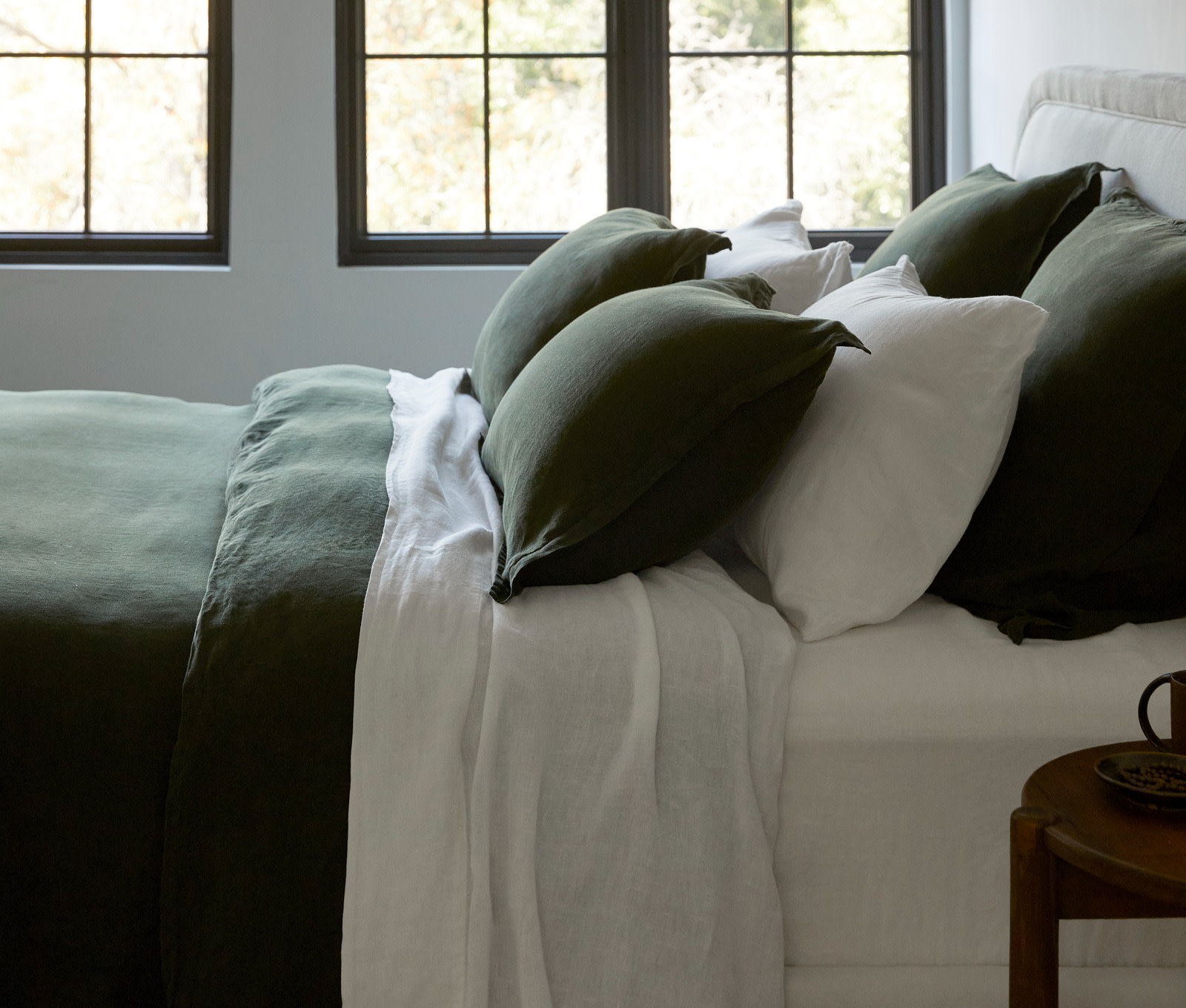 A bed filled with white linen pillows