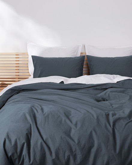 A neat bed with dusk blue and light grey mist brushed cotton sheets